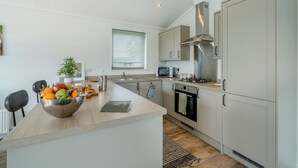 Una cocina moderna con una isla central, electrodomésticos de acero inoxidable y un ventanal con persianas.
