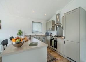 A modern kitchen with a central island, stainless steel appliances, and a window with blinds.