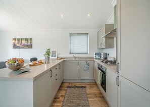 A modern kitchen with a wooden countertop, a bowl of fruit, a toaster, and a window with blinds.