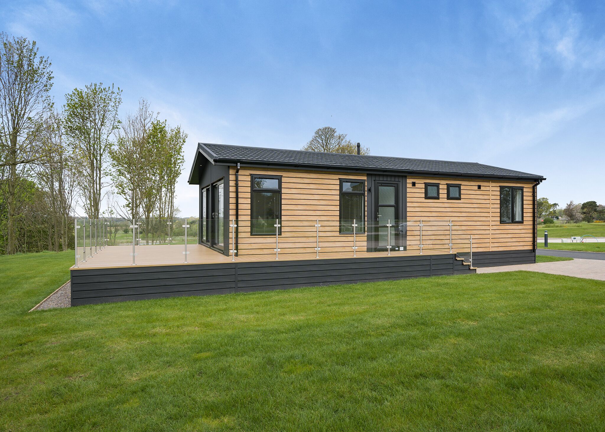 A modern, single-story building with a flat roof, large windows, and a wooden facade.