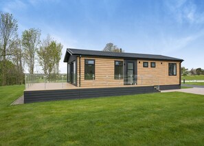 Un bâtiment moderne, de plain-pied, doté d’un toit plat, de grandes fenêtres et d’une façade en bois.