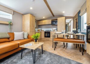 A modern kitchen with wooden cabinets, a built-in microwave, and a dining area with a bench. - Spacious, light and contemporary lodge. (Moffat)
