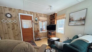Una sala de estar acogedora con pared de madera, un televisor y un cuadro.