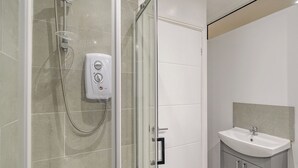 A modern bathroom with a glass-enclosed shower, a handheld showerhead, a soap dispenser, and a sink with a mirror. - Beacon Fell Cottage 2 (Longridge, Ribble Valley)