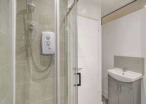 A modern bathroom with a glass-enclosed shower, a handheld showerhead, a soap dispenser, and a sink with a mirror. - Beacon Fell Cottage 2 (Longridge, Ribble Valley)