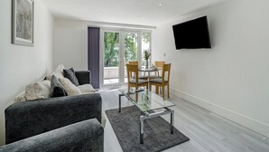 A modern living room with a sofa, a glass coffee table, and a dining area with chairs and a table. - Beacon Fell Cottage 2 (Longridge, Ribble Valley)