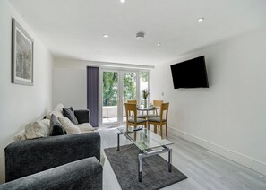 A modern living room with a sofa, a glass coffee table, and a dining area with chairs and a table. - Beacon Fell Cottage 2 (Longridge, Ribble Valley)