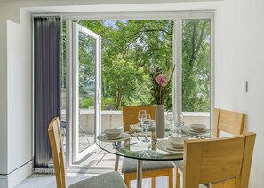 A dining area with a glass table, chairs, and a vase with flowers. - Beacon Fell Cottage 2 (Longridge, Ribble Valley)