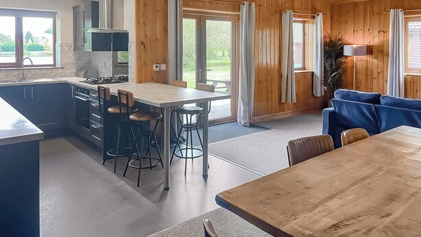 A modern kitchen with a central island, bar stools, and a dining table.