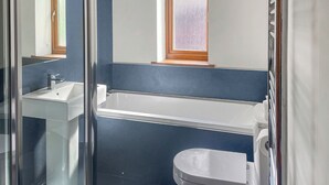 A bathroom with a glass shower enclosure, a white sink, a bathtub, and a toilet.
