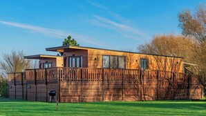 A modern wooden cabin with a deck, large windows, and a fenced yard. - 1 bedroom accommodation in Ely (Ely)