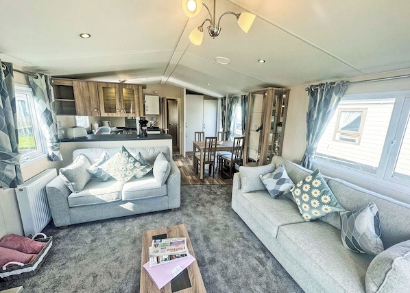 A cozy living room with two sofas, a coffee table, and a kitchen area in the background.