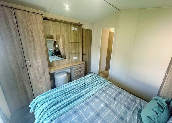 Un dormitorio con cama, armario, espejo y escritorio.