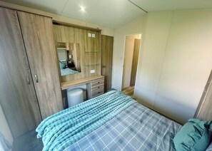 A bedroom with a bed, a wardrobe, a mirror, and a desk.