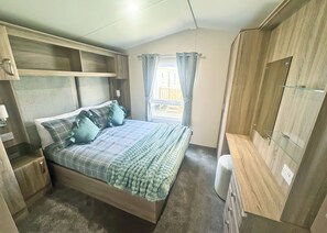 A bedroom with a bed, bedside tables, a wardrobe, and a window with curtains.