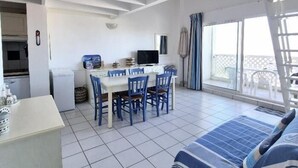 A room with a dining table and chairs, a bed, a TV, and a balcony with chairs. - Apartment with sea view and private pool (FOURAS)