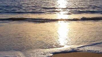 Une plage avec des vagues et la lumière du soleil se reflétant sur l’eau.