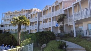 A multi-story hotel with balconies, palm trees, and a pool area. - Apartment with sea view and private pool (FOURAS)