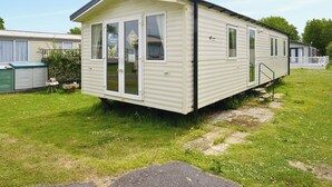 Ein Bungalow mit Satteldach, einer Veranda und einer kleinen Terrasse.