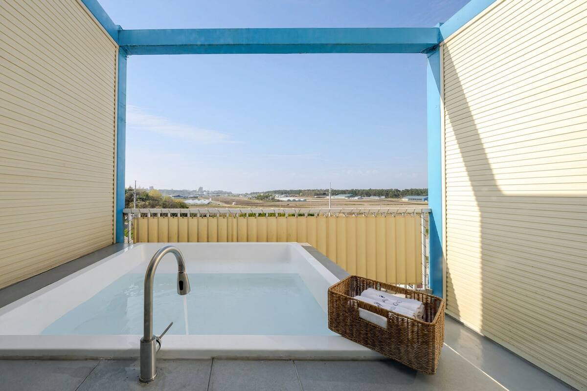 A balcony with a hot tub, a metal faucet, and a wicker basket.