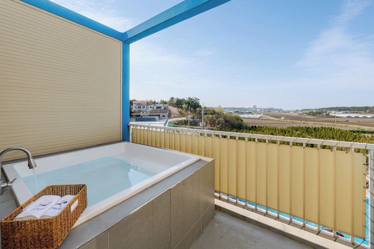 Un balcon avec une baignoire, un panier en osier et une vue sur le paysage.