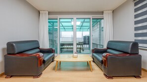Ett rum med två läderfåtöljer, ett litet träbord och en glasdörr som leder ut till ett utomhusområde.