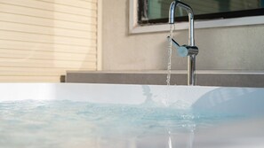 Une salle de bain moderne avec une baignoire, un robinet et une fenêtre avec des stores.