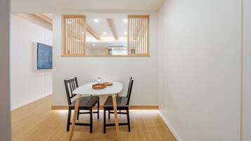 A dining area with a white table, two chairs, and a wooden floor.