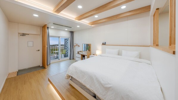 Een moderne hotelkamer met een groot bed, een bureau en een schuifdeur naar een balkon.