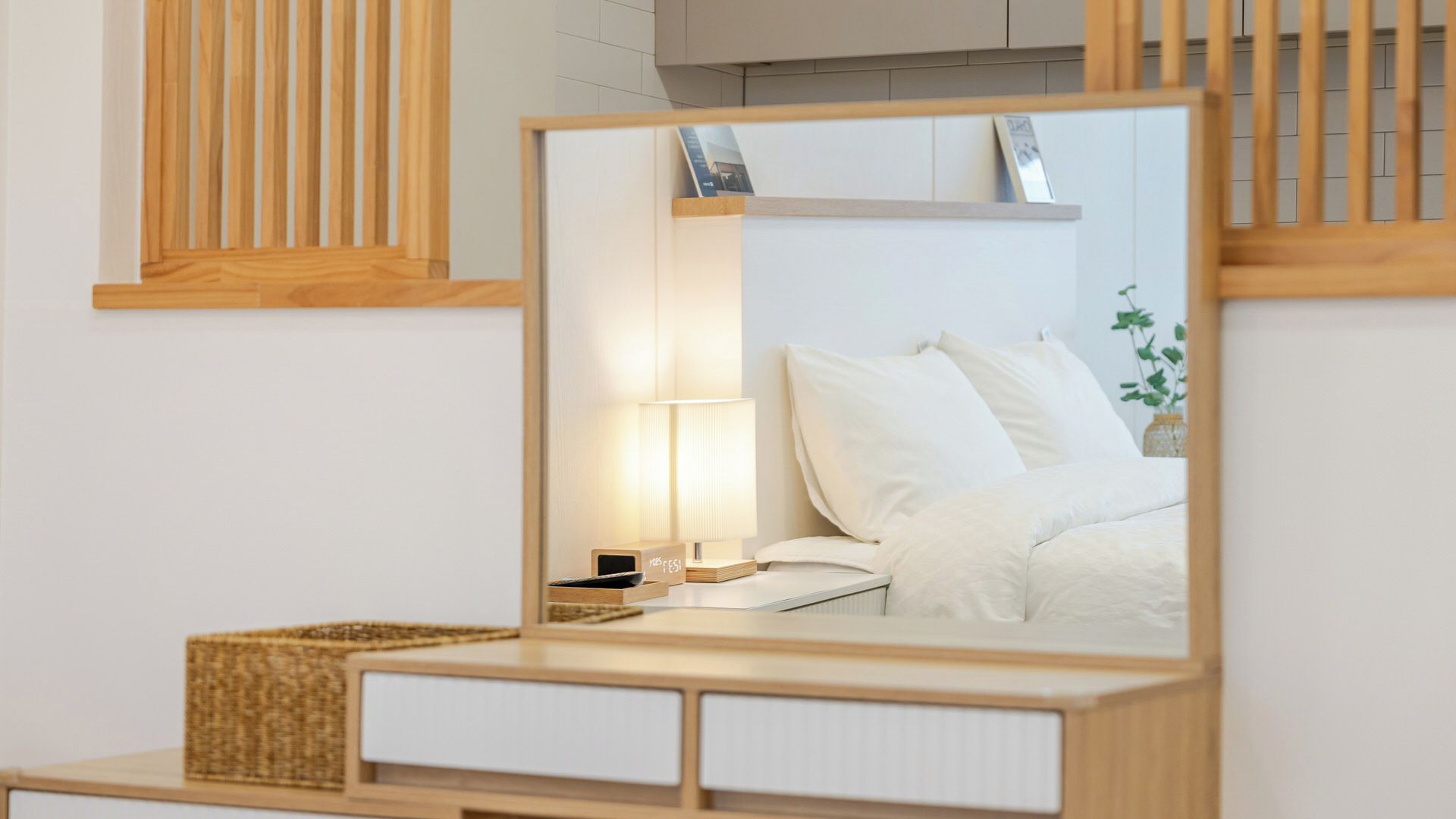 Un dormitorio con cama, mesita de noche, lámpara y un espejo que refleja la habitación.