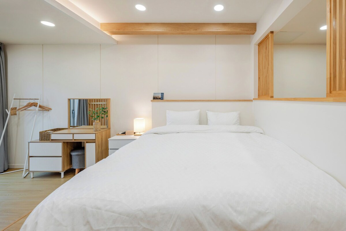 Une chambre à coucher comprenant un lit, une table de chevet, une lampe et un bureau avec une chaise.