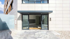 Una entrada de edificio moderna con puerta de cristal y suelo de baldosas.