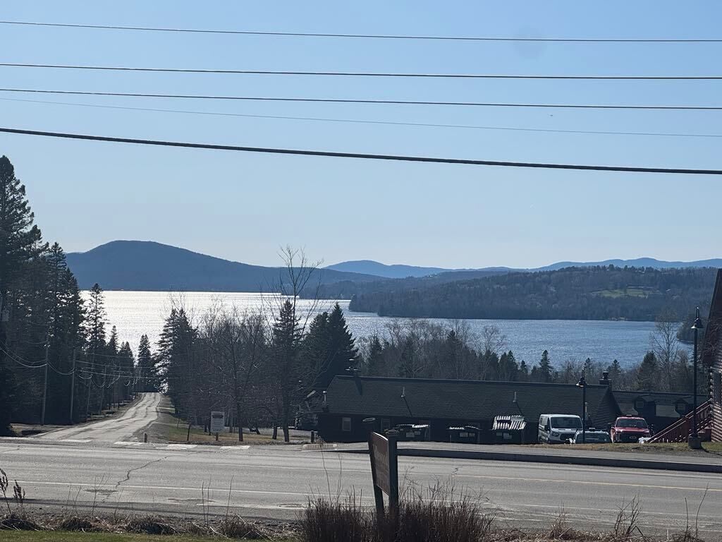 Una carretera que lleva a un edificio con vistas a un lago y montañas.