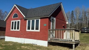 A red wooden house with a white trim, a front porch, and a mailbox. - Idlewood Cabin 3 (Rangeley)