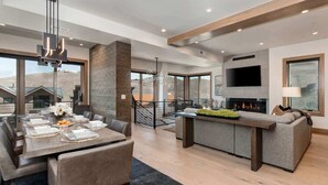 A modern interior with a dining area, a fireplace, a sofa, and a TV.