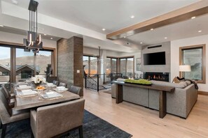 A modern interior with a dining area, a fireplace, a sofa, and a TV. - Abode at Powder King, ski-in/ski-out, hot tub, fire pit, PCMR (Park City)