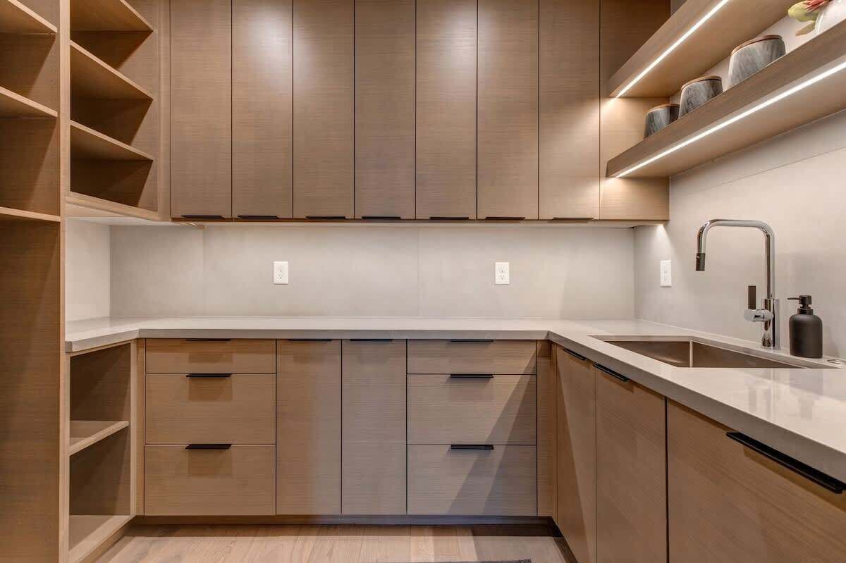 A modern kitchen with wooden cabinets, a white countertop, and a stainless steel faucet.
