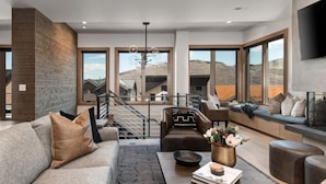 A modern living room with a sofa, coffee table, and seating area with a view of the landscape.
