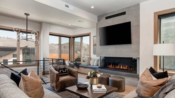 A modern living room with a fireplace, comfortable seating, and large windows.