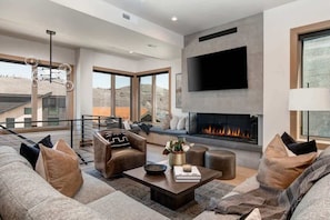 Una sala de estar moderna con chimenea, asientos cómodos y ventanas amplias.