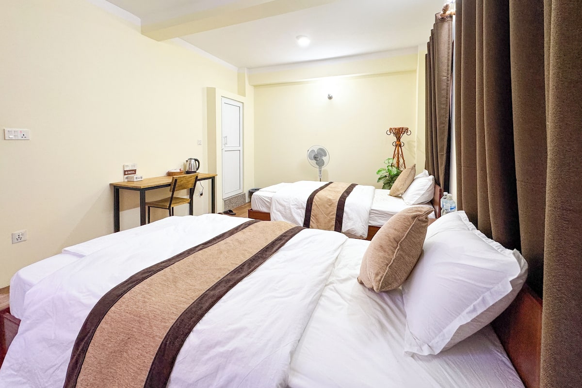 Una camera d'albergo con due letti, una scrivania e una sedia.