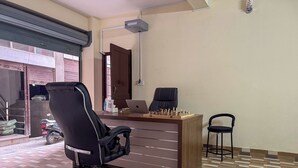 Een kamer met een houten bureau, een zwarte bureaustoel, een laptop en een schaakbord.