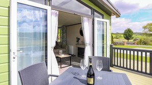 A balcony with a table, two chairs, a bottle of wine, and two glasses.