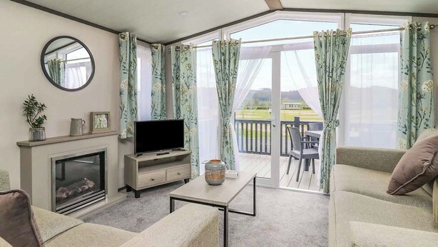 A living room with a fireplace, television, and a balcony with outdoor furniture.