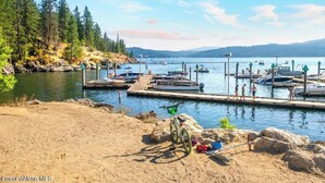 A lakeside dock with boats, a bicycle, and a sandy beach. - Charming 2-bedroom bungalow in the heart of Coeur d'Alene with backyard oasis (Coeur d'Alene)