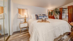 A bedroom with a bed, bedside table, lamp, and a window with curtains. - Charming 2-bedroom bungalow in the heart of Coeur d'Alene with backyard oasis (Coeur d'Alene)