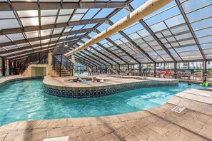 An indoor swimming pool with a glass ceiling, tiled edges, and a stone floor. - Oceanview Vibes! Compass Cove Studio Retreat (Myrtle Beach)