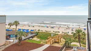 A beach view with a wooden boardwalk, beach umbrellas, and a lifeguard station. - Oceanview Vibes! Compass Cove Studio Retreat (Myrtle Beach)