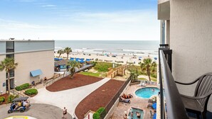 A pool area with a view of the beach, a golf cart, and a building with a balcony. - Oceanview Vibes! Compass Cove Studio Retreat (Myrtle Beach)