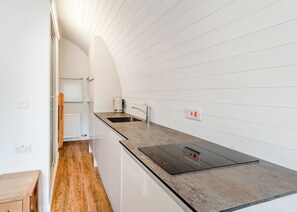 A modern kitchen with white cabinetry, a black countertop, and a built-in stove.